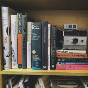 Books and a camera on a shelf.