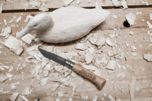 A wooden duck with a knife beside it.