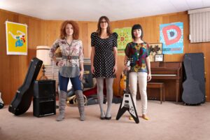Three woman standing together in a music room.